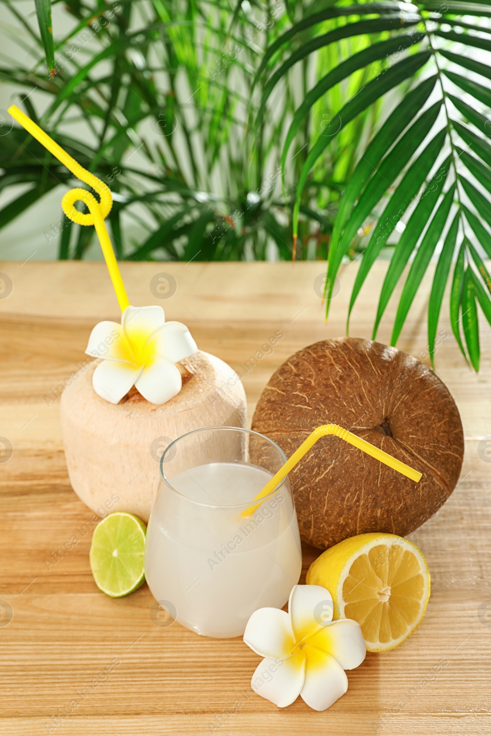 Photo of Composition with glass of coconut water on wooden table against blurred background