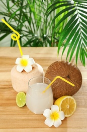 Photo of Composition with glass of coconut water on wooden table against blurred background