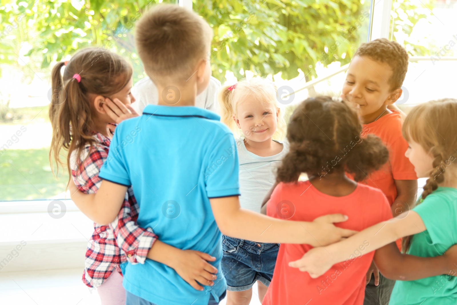 Photo of Little children making circle with hands around each other indoors. Unity concept