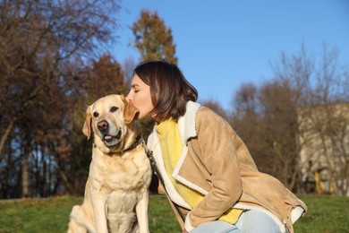 Photo of Beautiful young woman kissing cute Labrador Retriever on sunny day outdoors