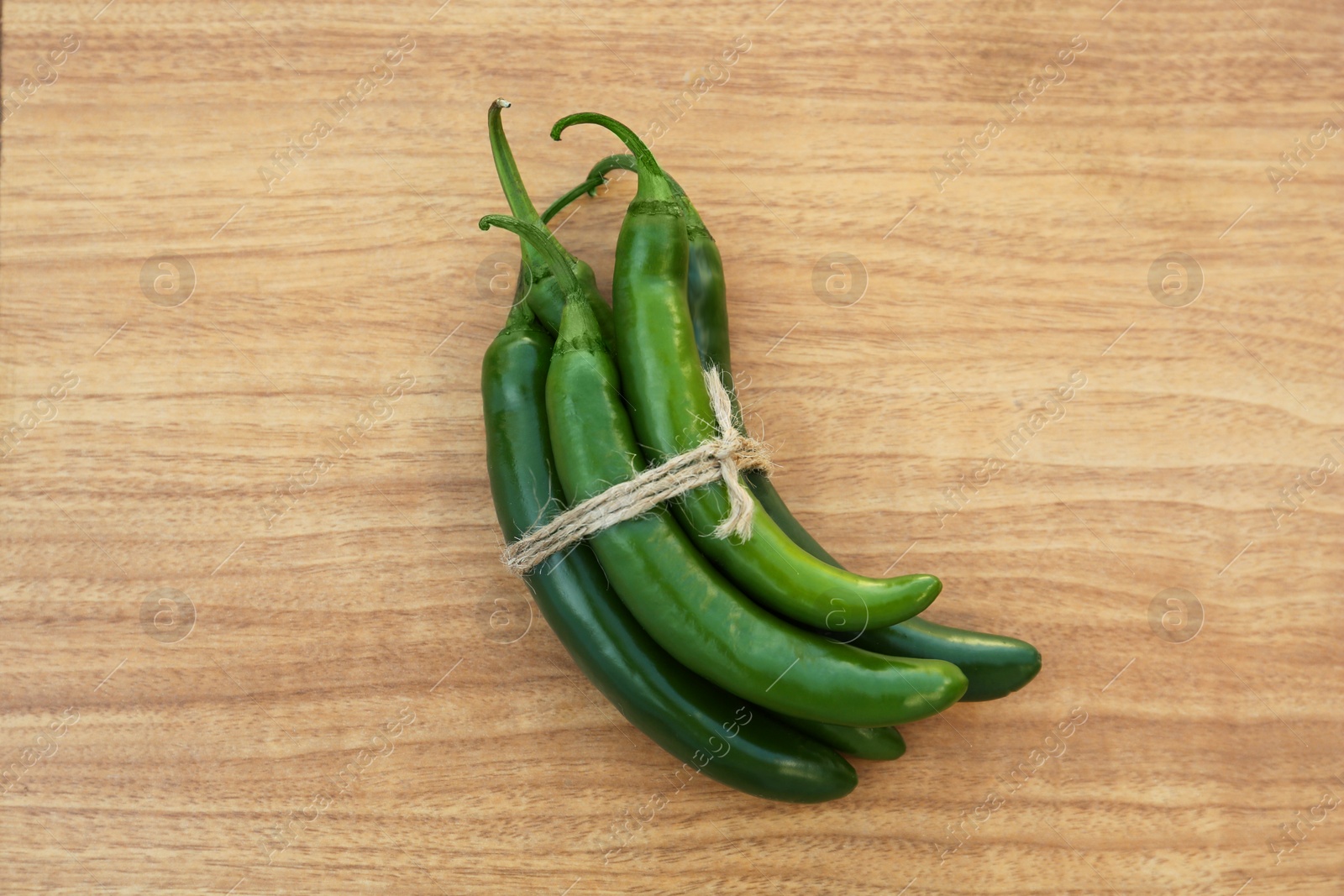 Photo of Green ripe chili peppers on wooden table, top view