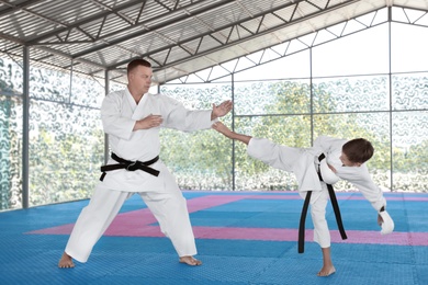 Photo of CHERNOMORKA, UKRAINE - JULY 10, 2020: Little boy with instructor practicing karate on training ground
