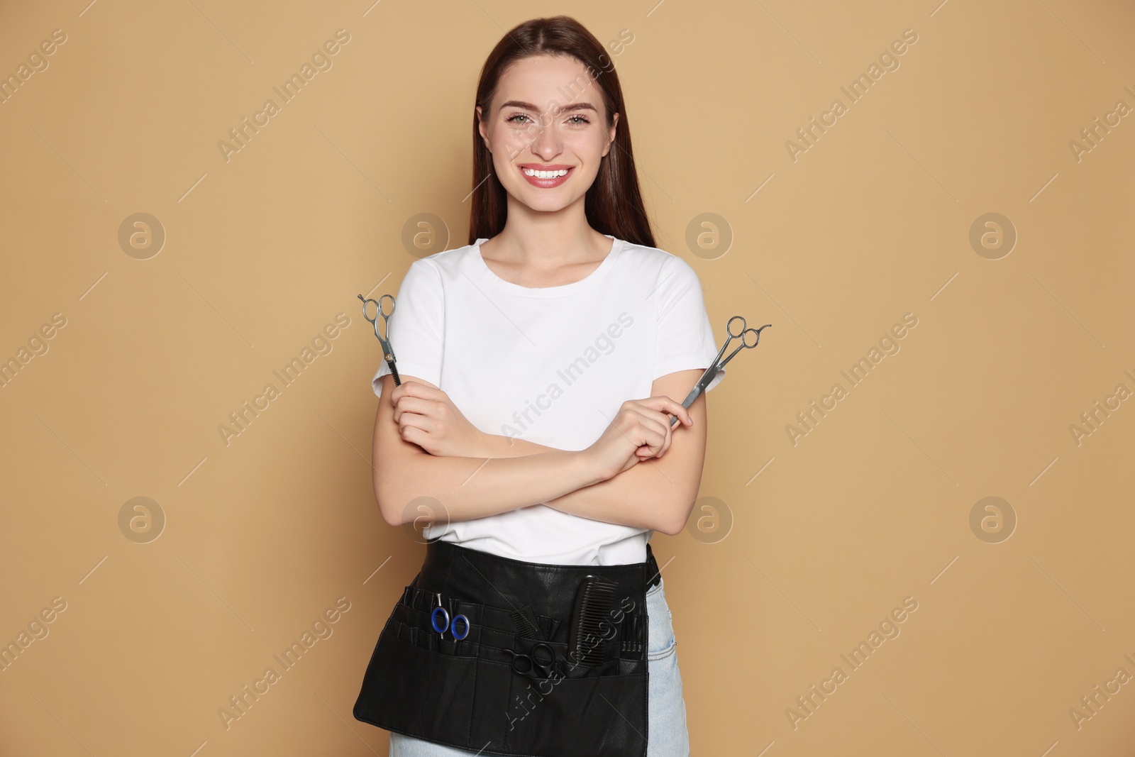 Photo of Portrait of happy hairdresser with professional scissors on beige background