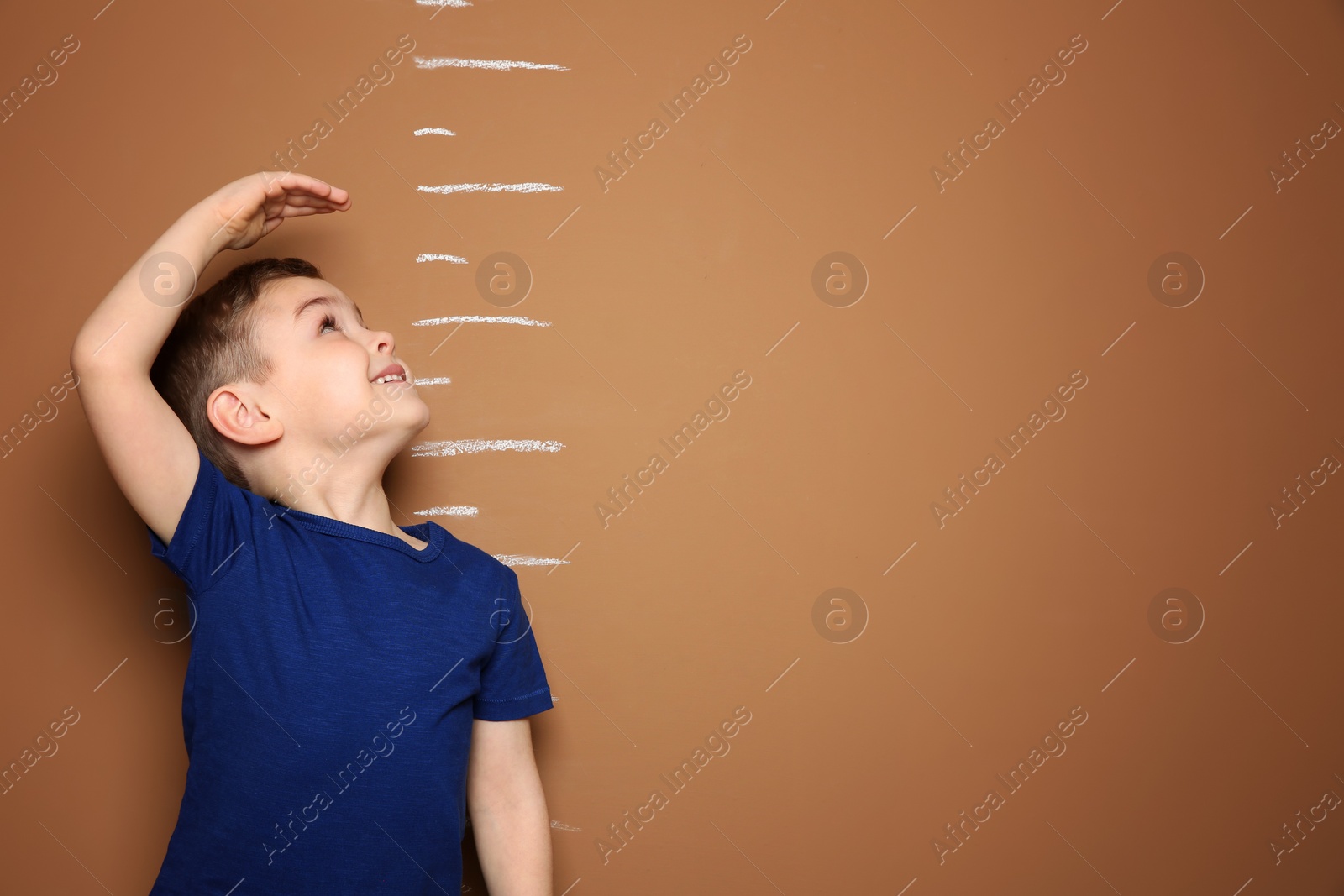 Photo of Little boy measuring his height on color background