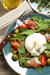 Photo of Delicious burrata salad served on wooden table, flat lay