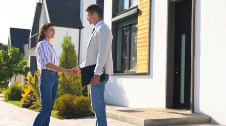 Photo of Real estate agent shaking hands with young woman outdoors