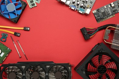 Frame of graphics card and other computer hardware on red background, flat lay. Space for text