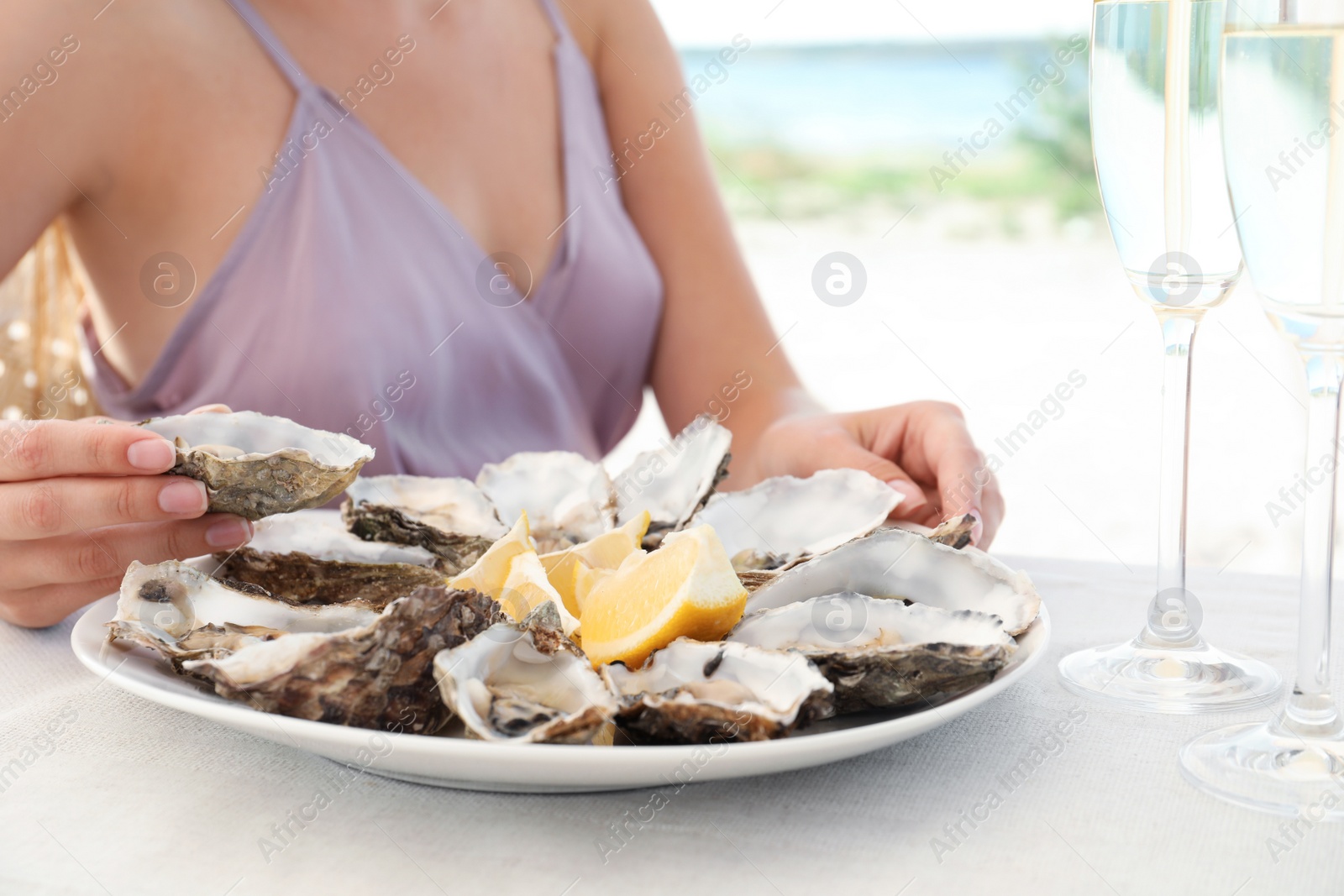 Photo of Woman with fresh oysters and cut juicy lemon at table