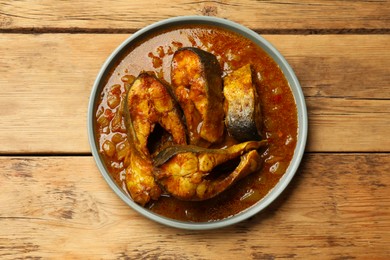 Photo of Tasty fish curry on wooden table, top view. Indian cuisine