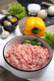 Photo of Raw chicken minced meat with basil on wooden table