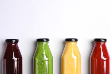 Photo of Bottles with delicious colorful juices on white background, flat lay