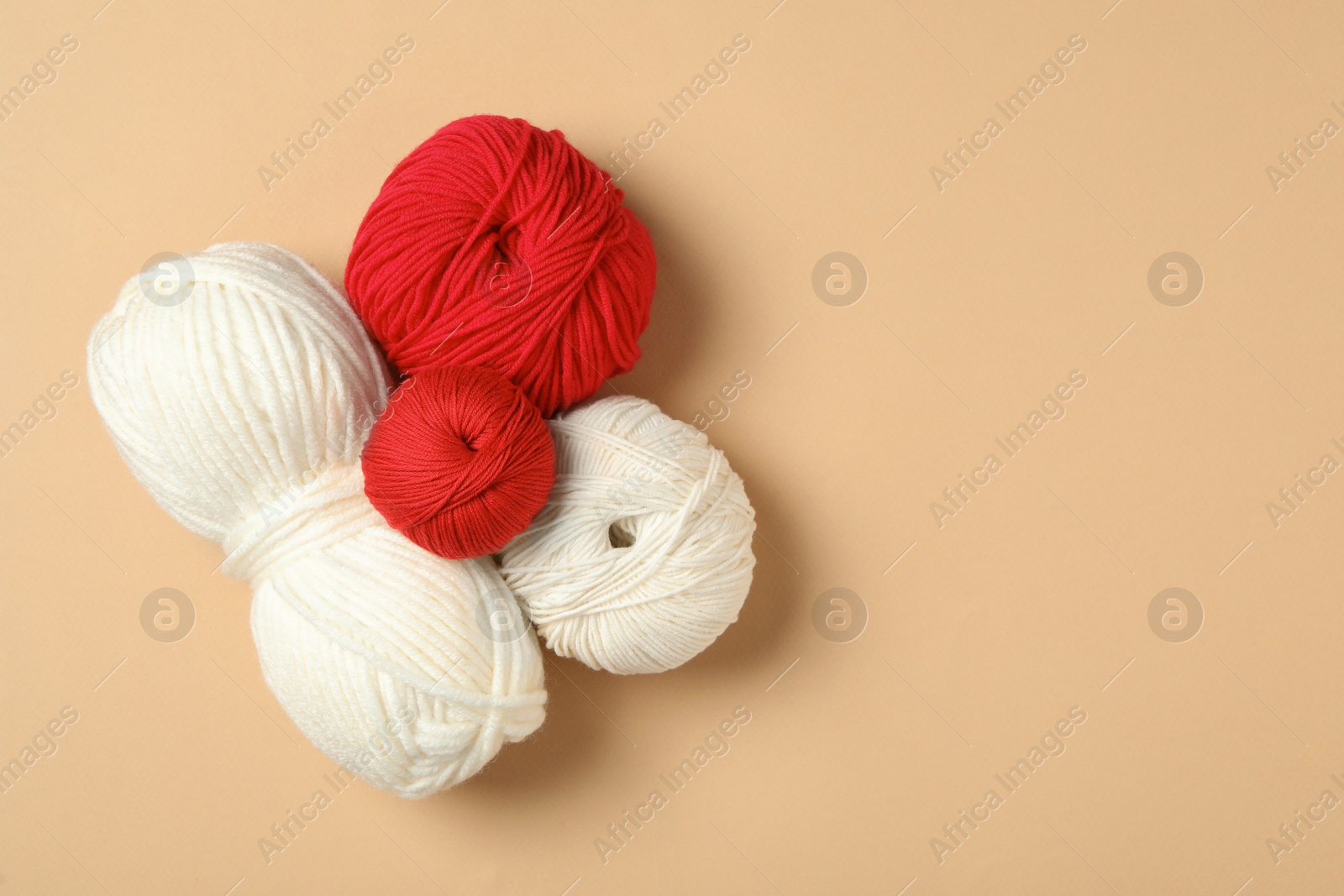 Photo of Soft woolen yarns on beige background, flat lay. Space for text