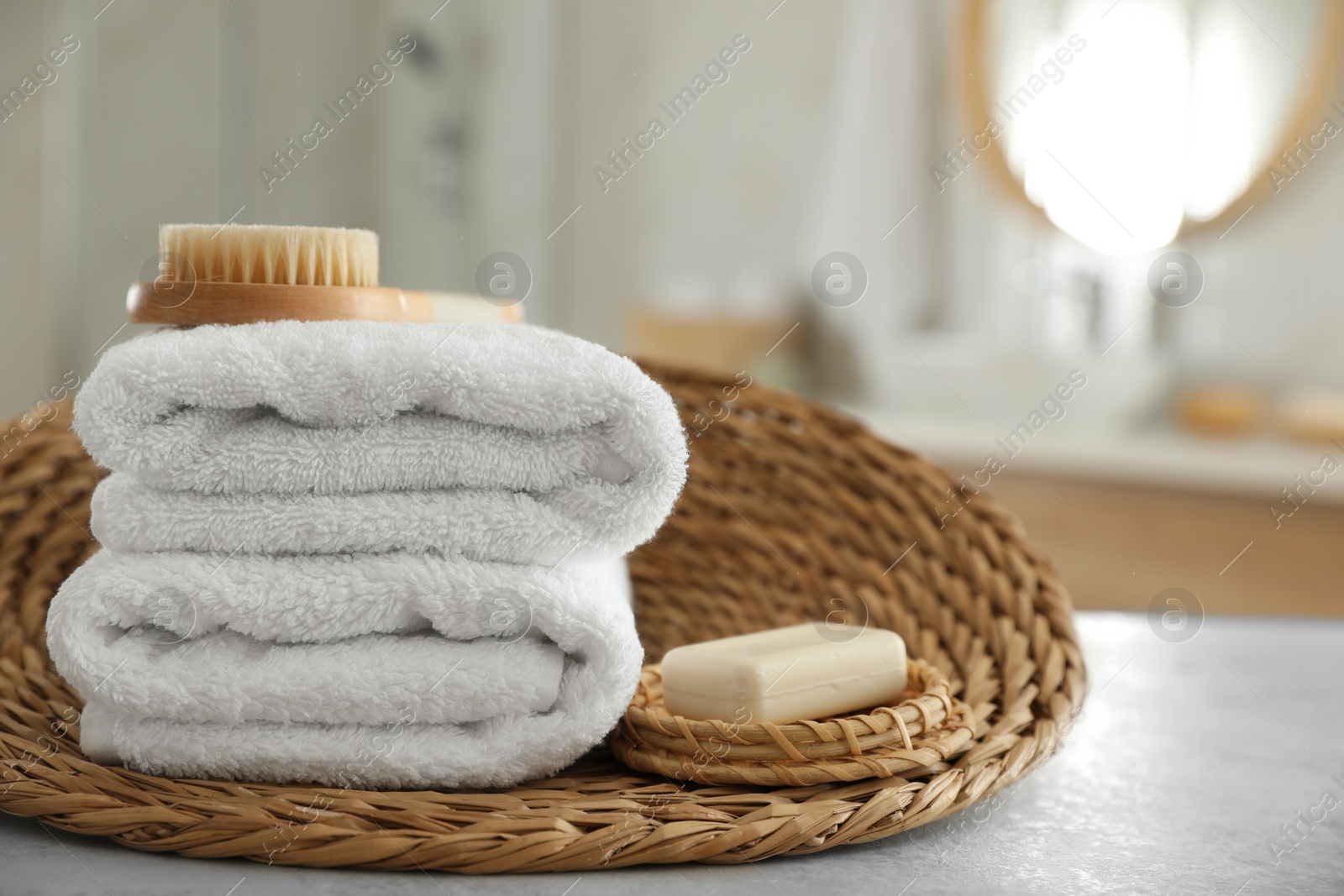 Photo of Wicker tray with clean towels on table in bathroom