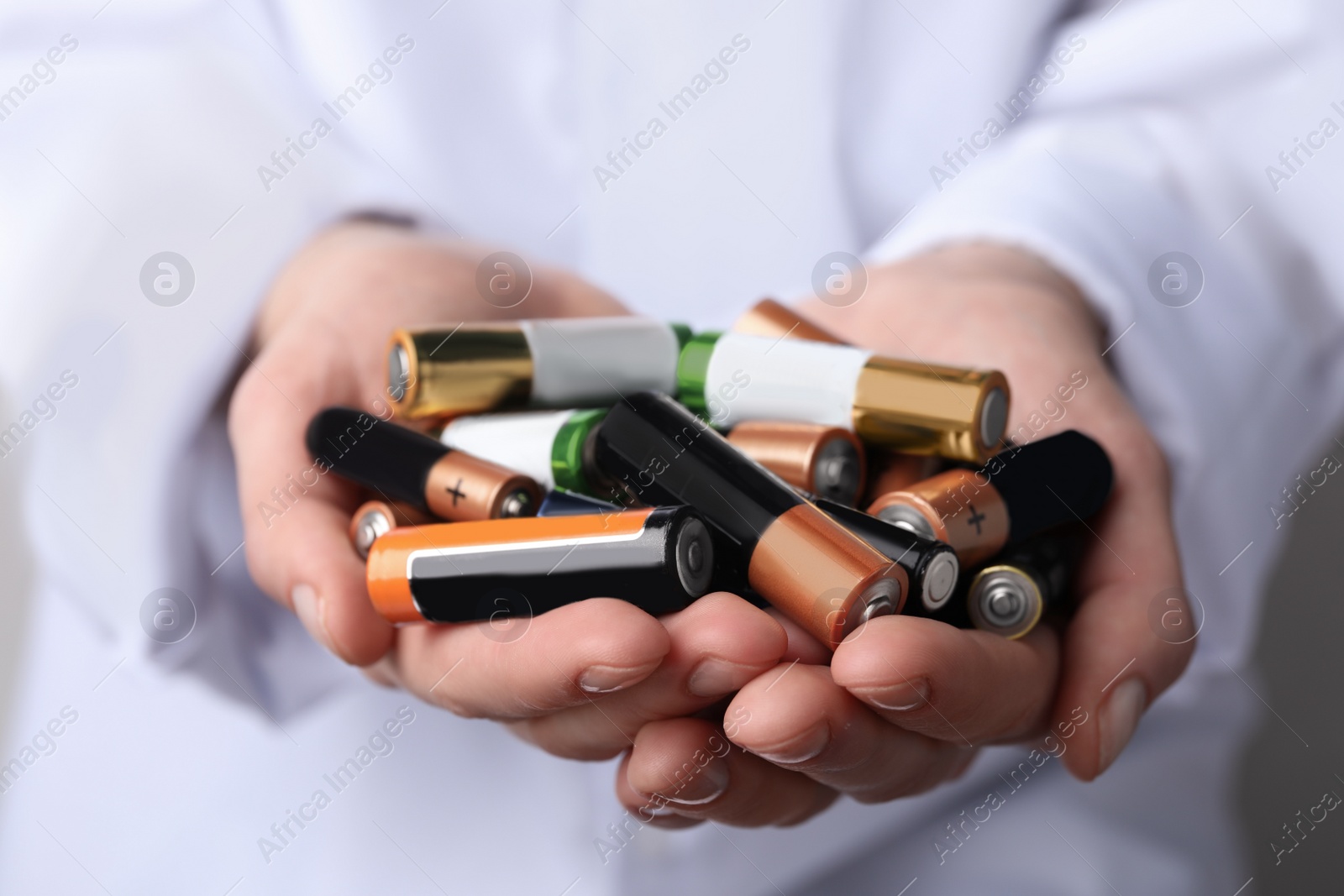 Image of Woman holding many used electric batteries in her hands, closeup