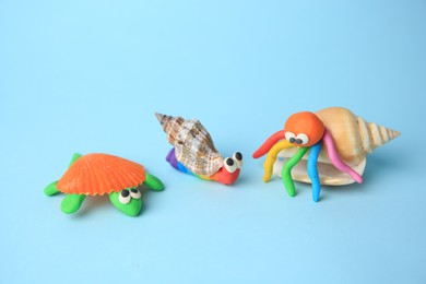 Photo of Turtle, snail and crab made from plasticine on light blue background. Children's handmade ideas