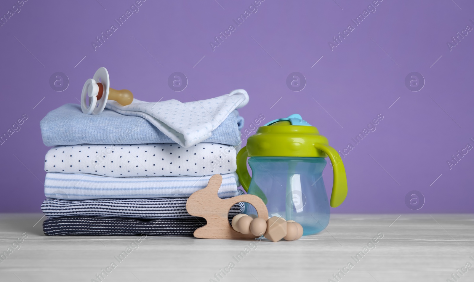 Photo of Children's accessories and stack of clothes on white wooden table