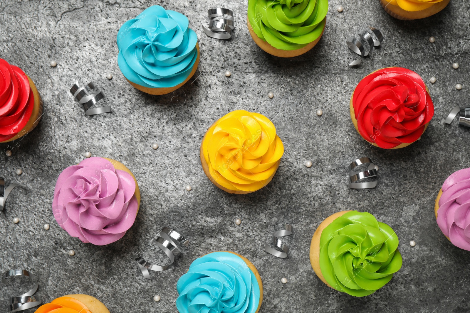 Photo of Flat lay composition with colorful birthday cupcakes on grey table