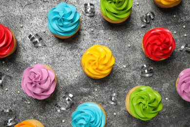 Flat lay composition with colorful birthday cupcakes on grey table