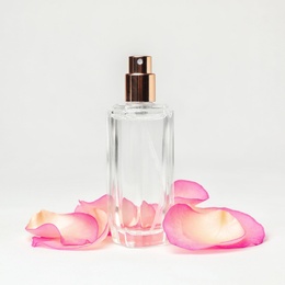 Photo of Transparent bottle of perfume and flower petals on white background