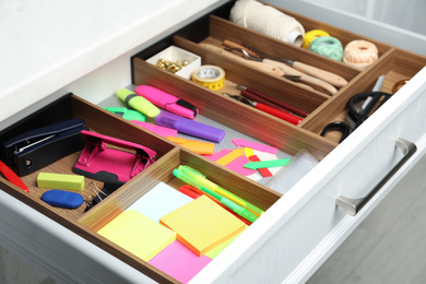 Stationery and sewing accessories in open desk drawer indoors