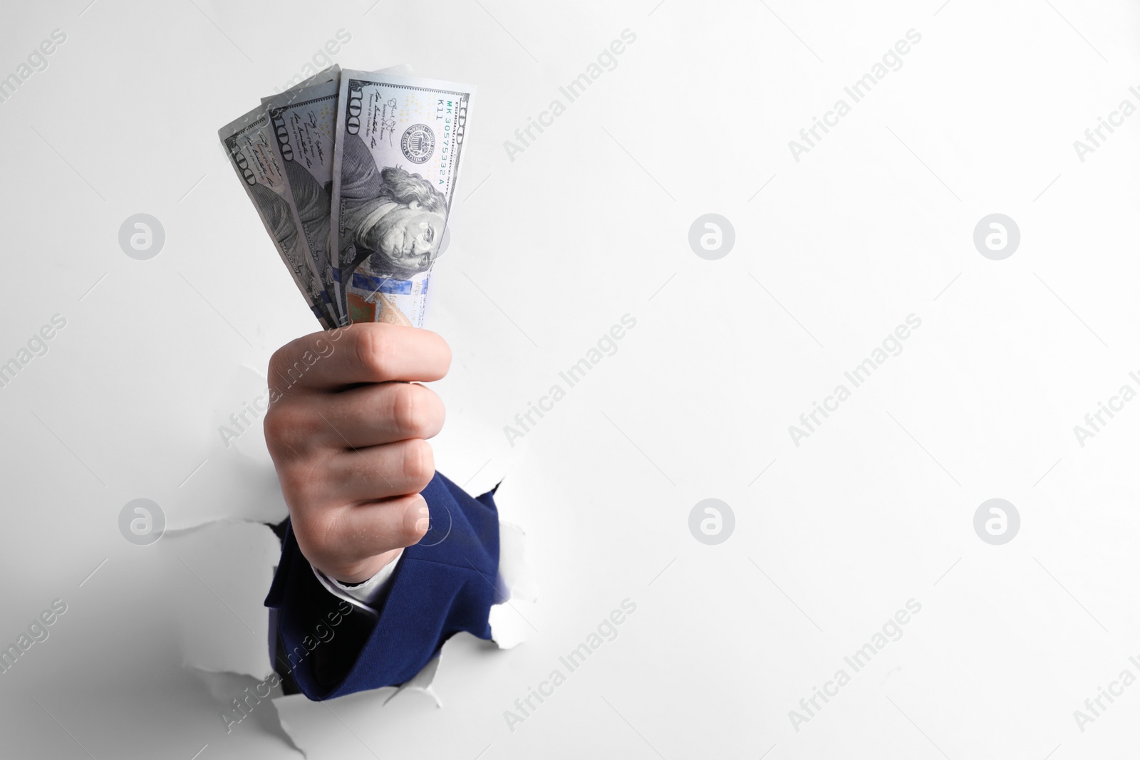 Photo of Businessman breaking through white paper with money in fist, closeup. Space for text