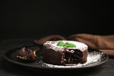 Delicious fresh fondant with hot chocolate and mint on black table, closeup