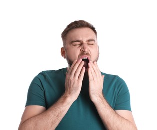 Sleepy young man yawning on white background