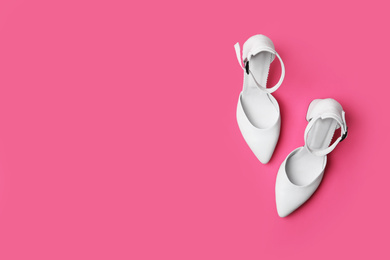 Photo of Stylish white female shoes on pink background, flat lay. Space for text