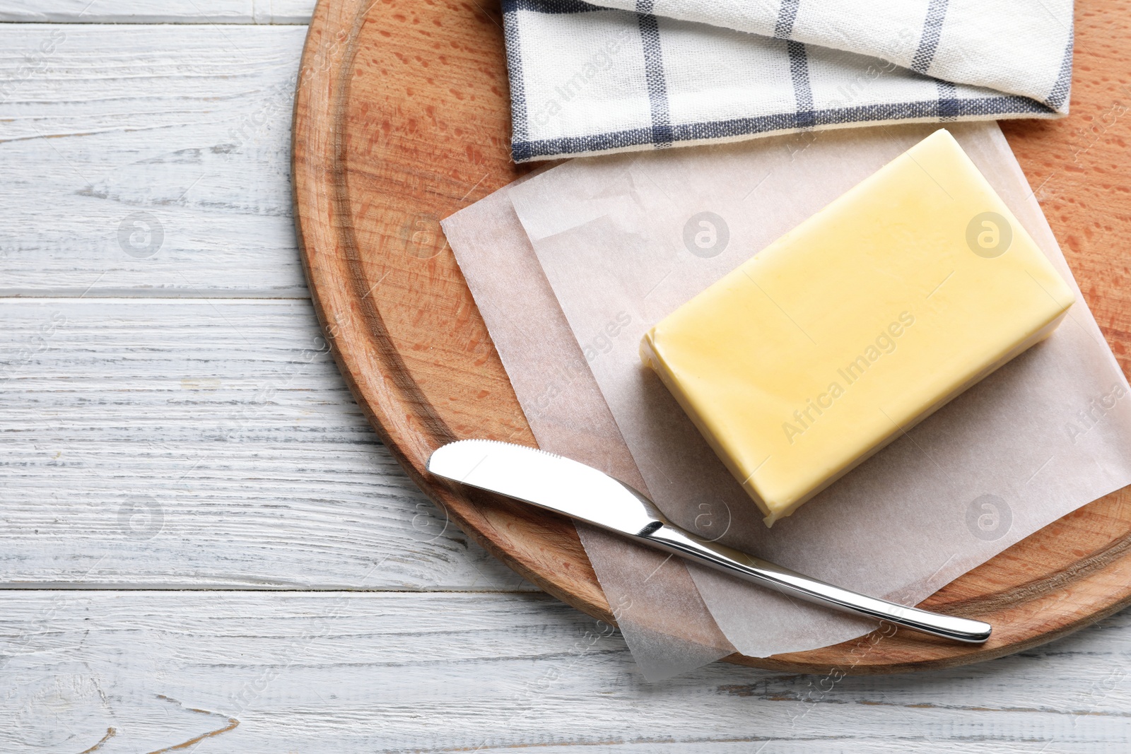 Photo of Wooden board with fresh butter and knife on table, top view. Space for text