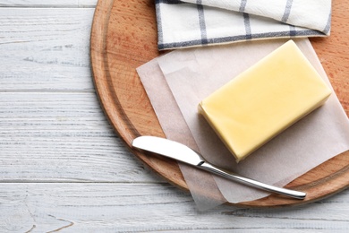 Wooden board with fresh butter and knife on table, top view. Space for text