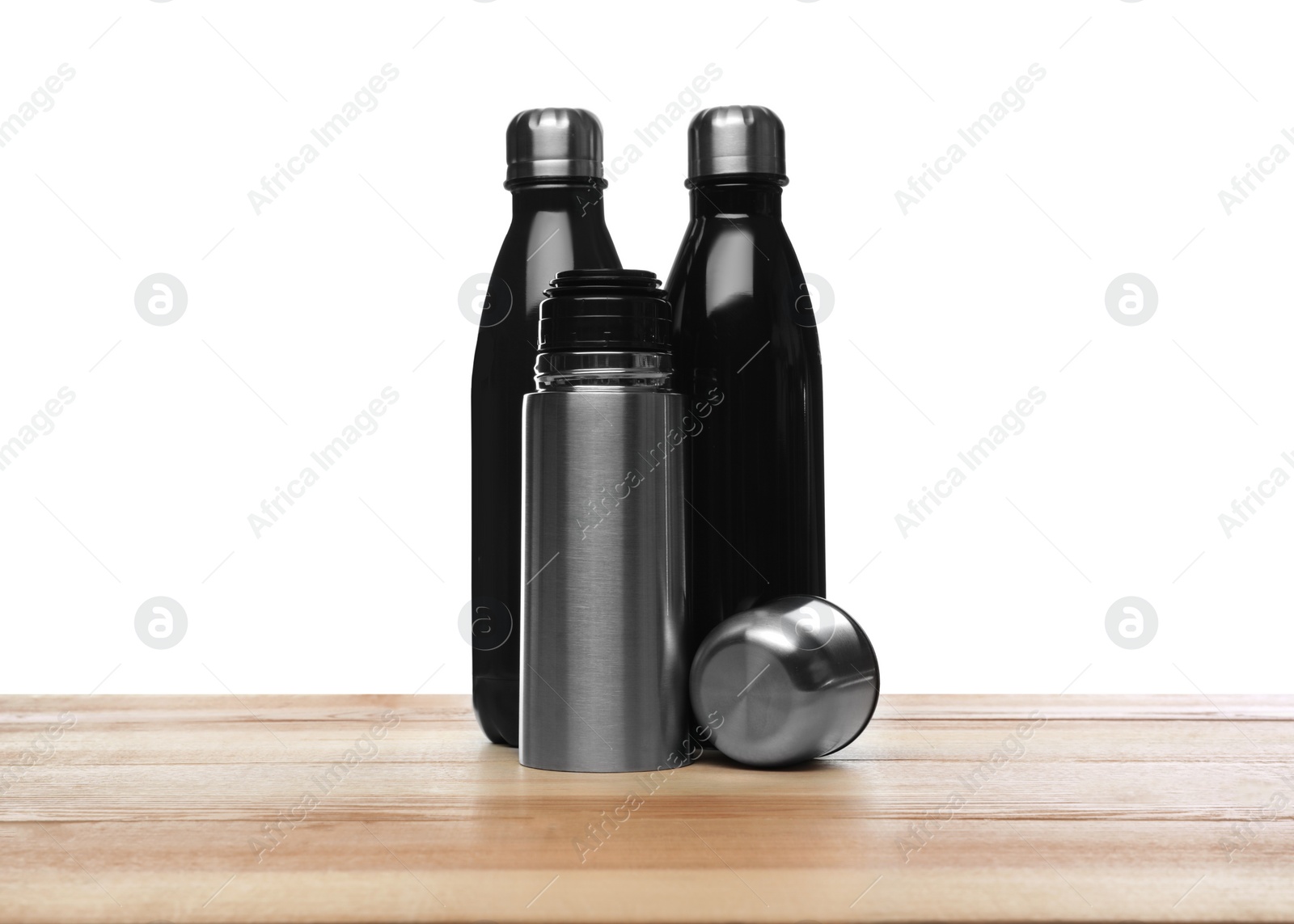 Photo of Stylish thermo bottles on wooden table against white background