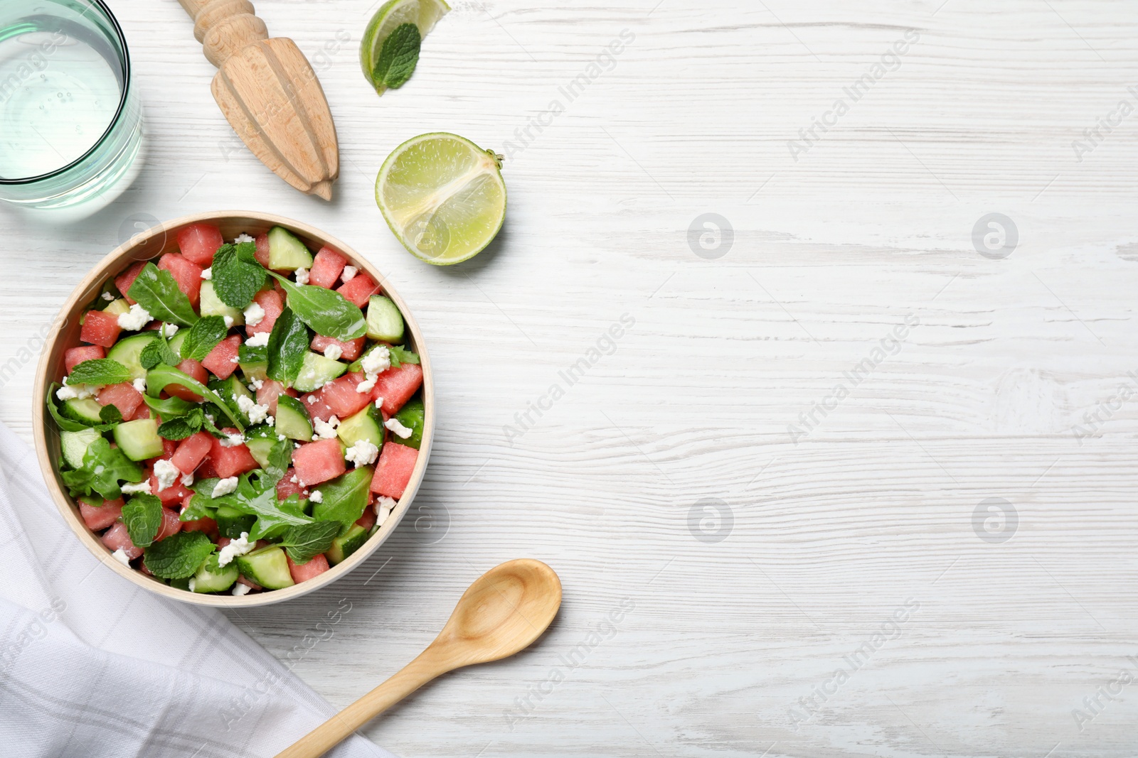 Photo of Delicious salad with watermelon, cucumber, arugula and feta cheese on white wooden table, flat lay. Space for text