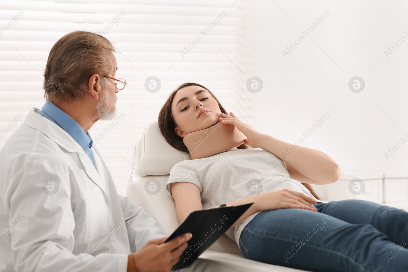 Photo of Orthopedist examining patient with injured neck in clinic