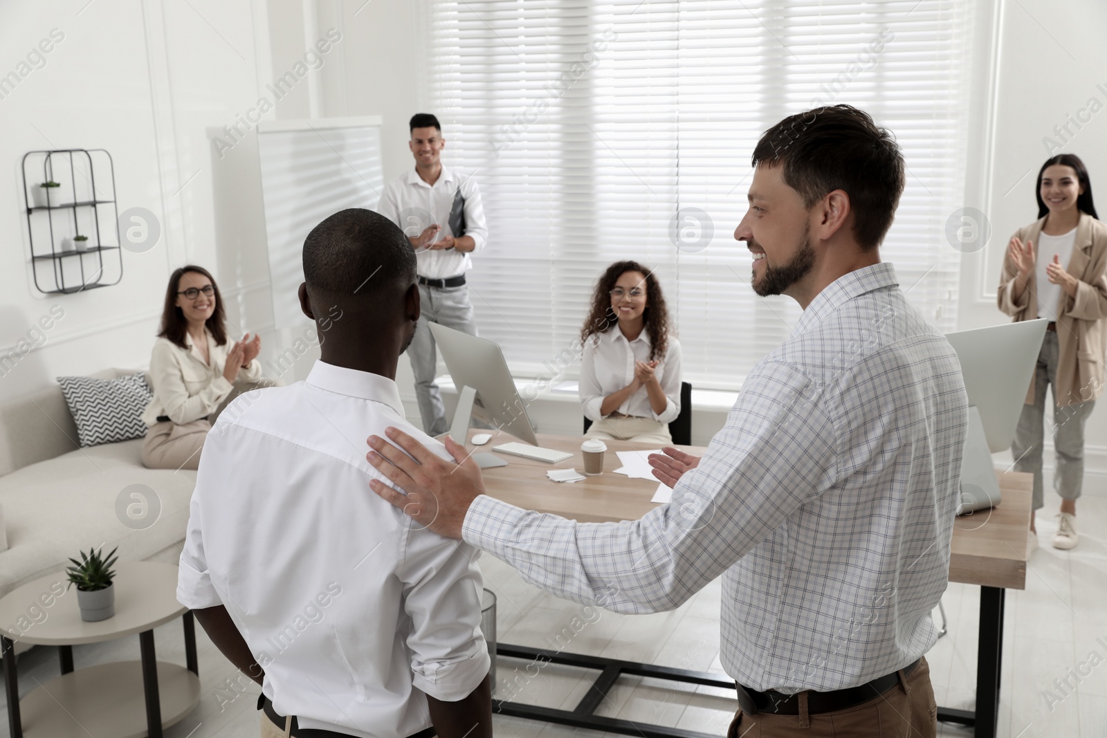 Photo of Boss introducing new employee to coworkers in office