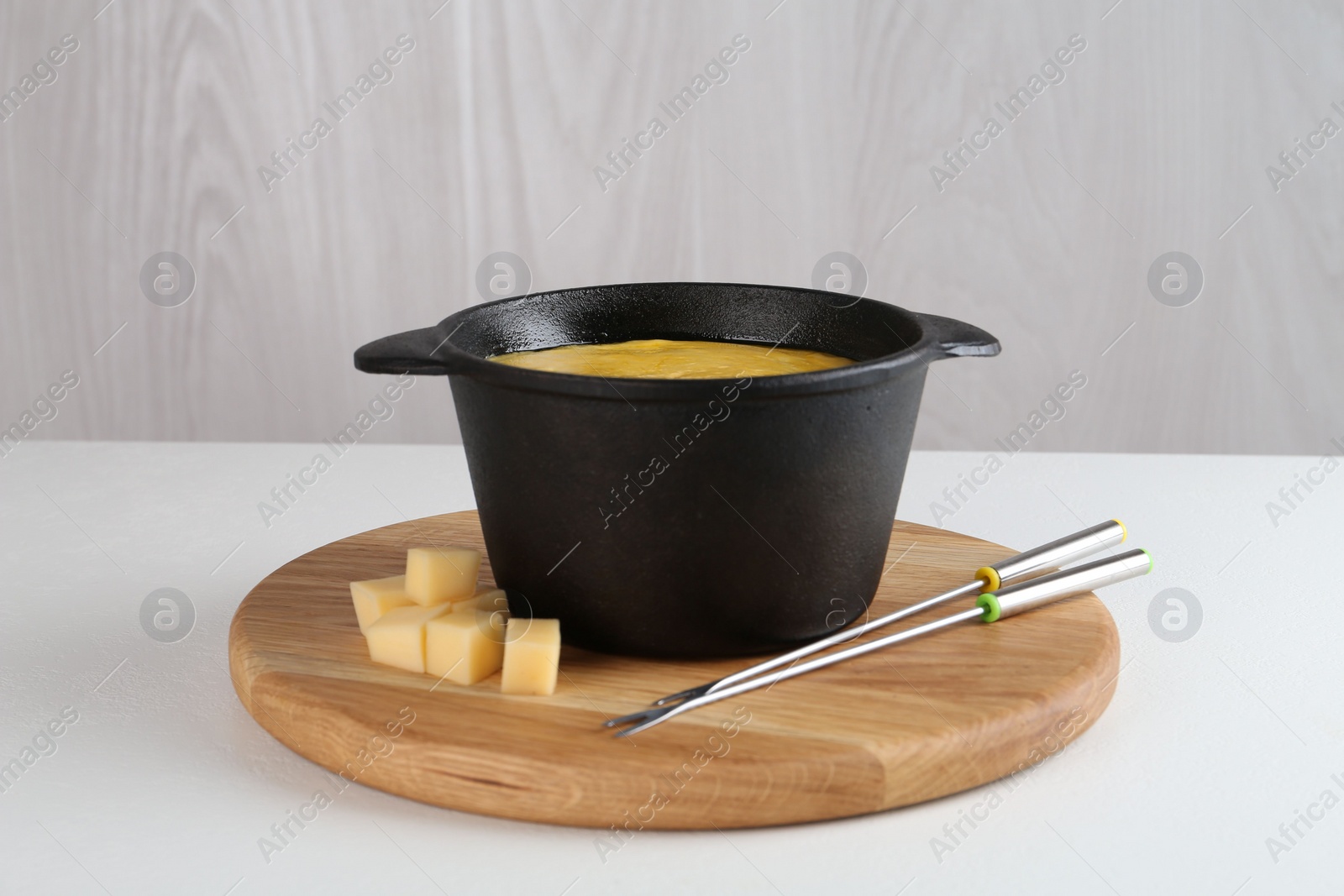 Photo of Fondue with tasty melted cheese and forks on white table