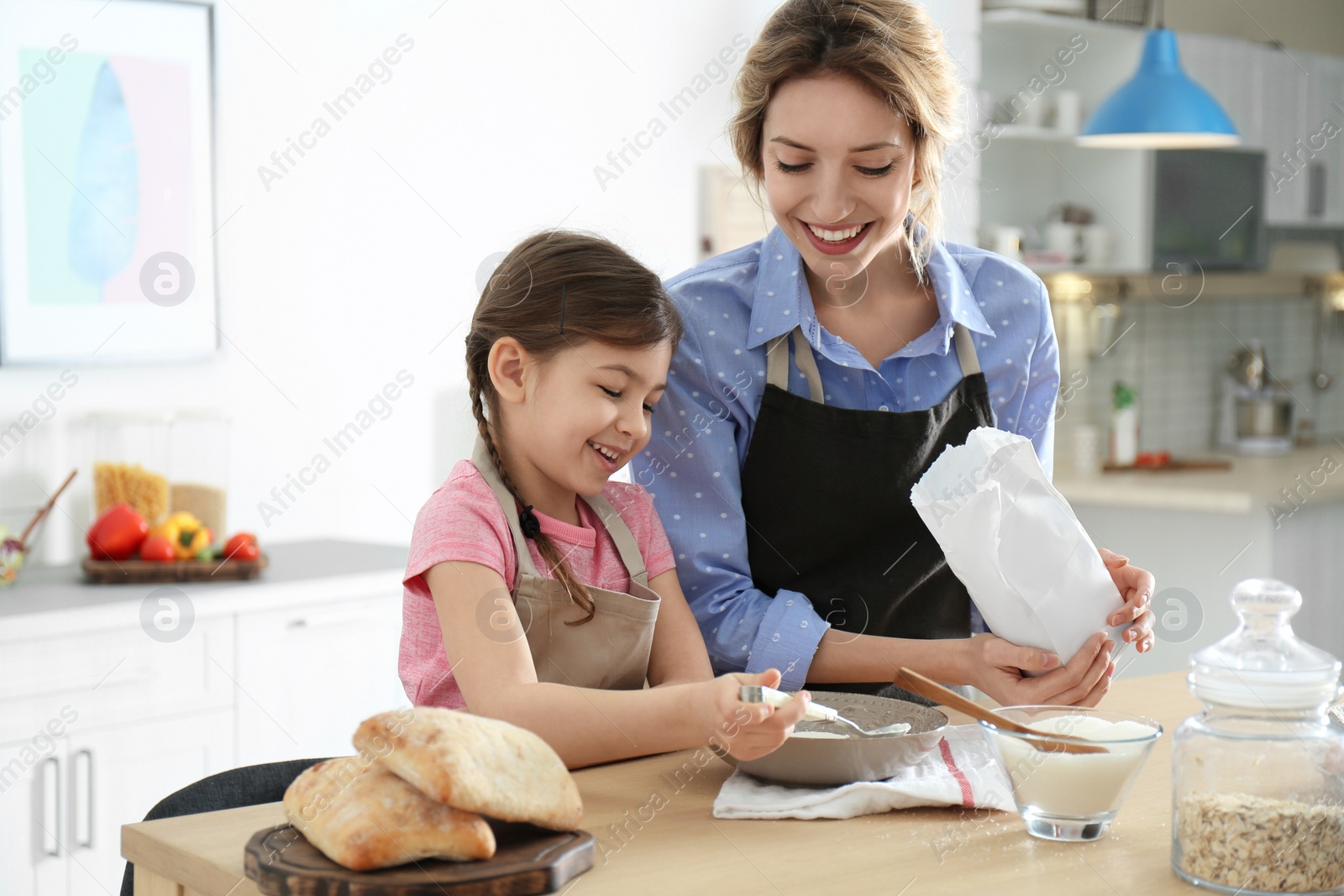 Photo of Young nanny with cute little girl cooking together in kitchen