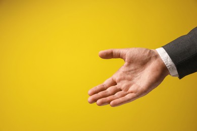 Photo of Man holding something in hand on yellow background, closeup. Space for text