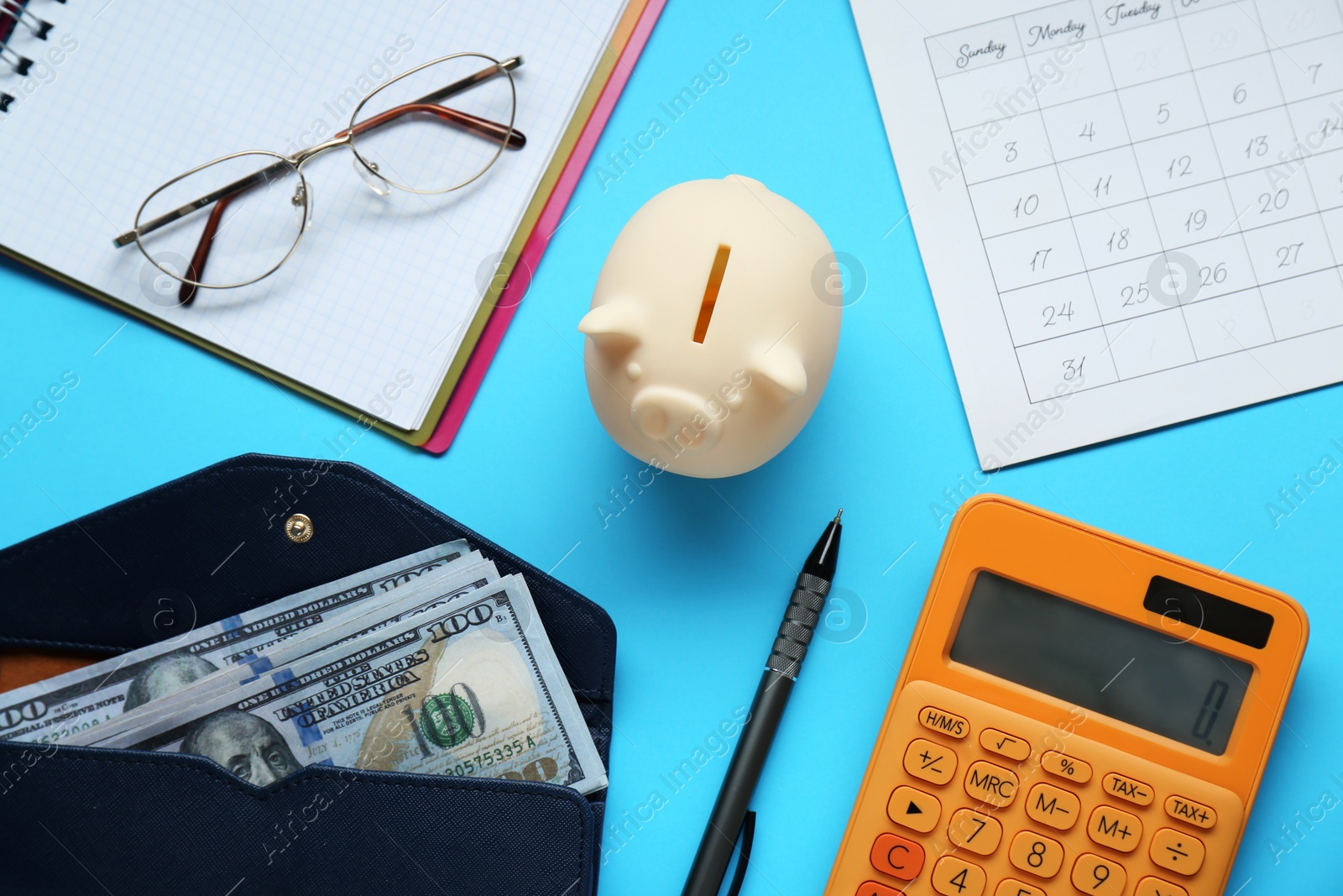 Photo of Flat lay composition with piggy bank and calculator on light blue background