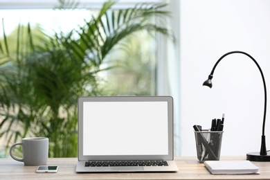 Photo of Modern laptop on desk in room. Home workplace