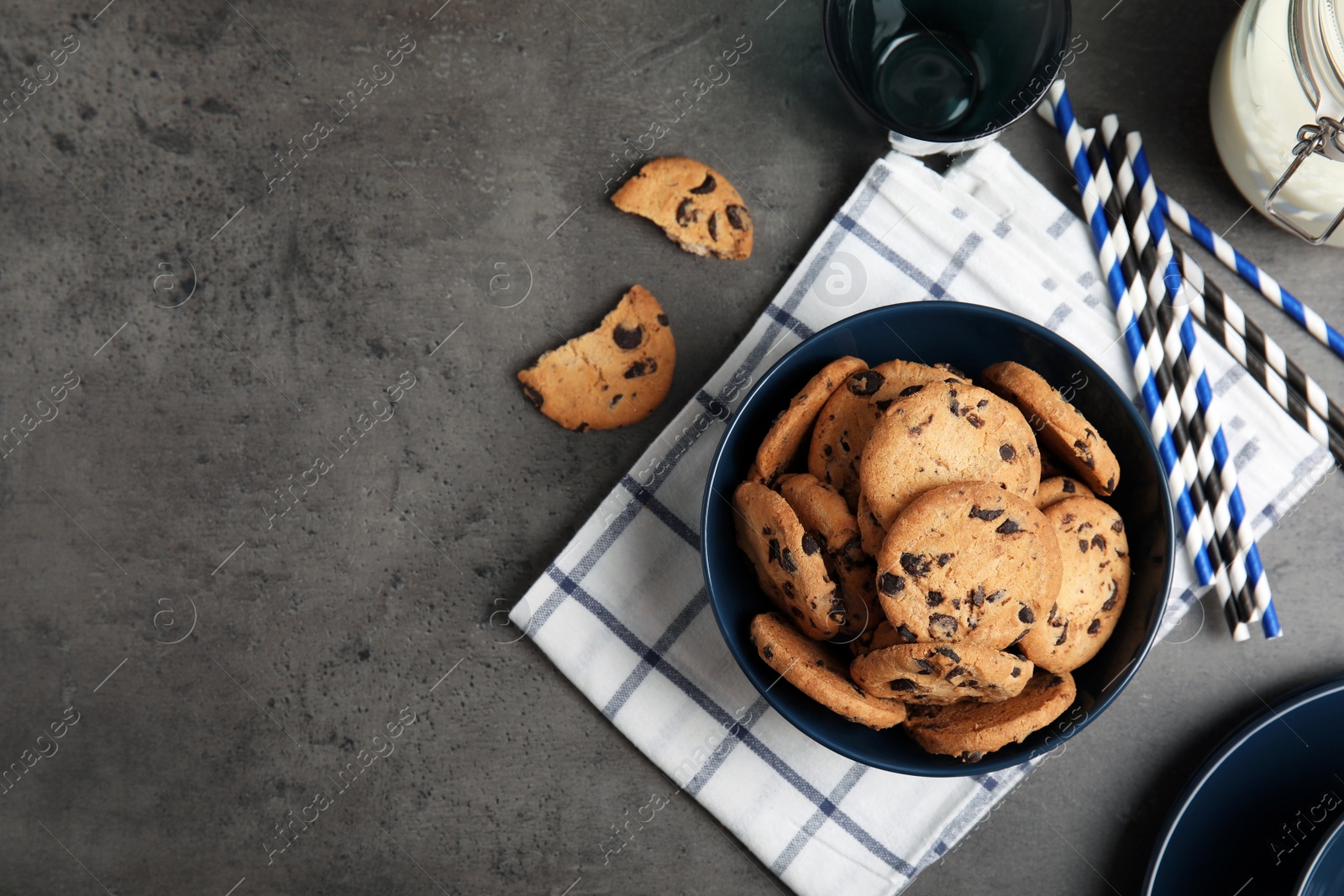 Photo of Flat lay composition with bowl of tasty chocolate chip cookies on grey table. Space for text