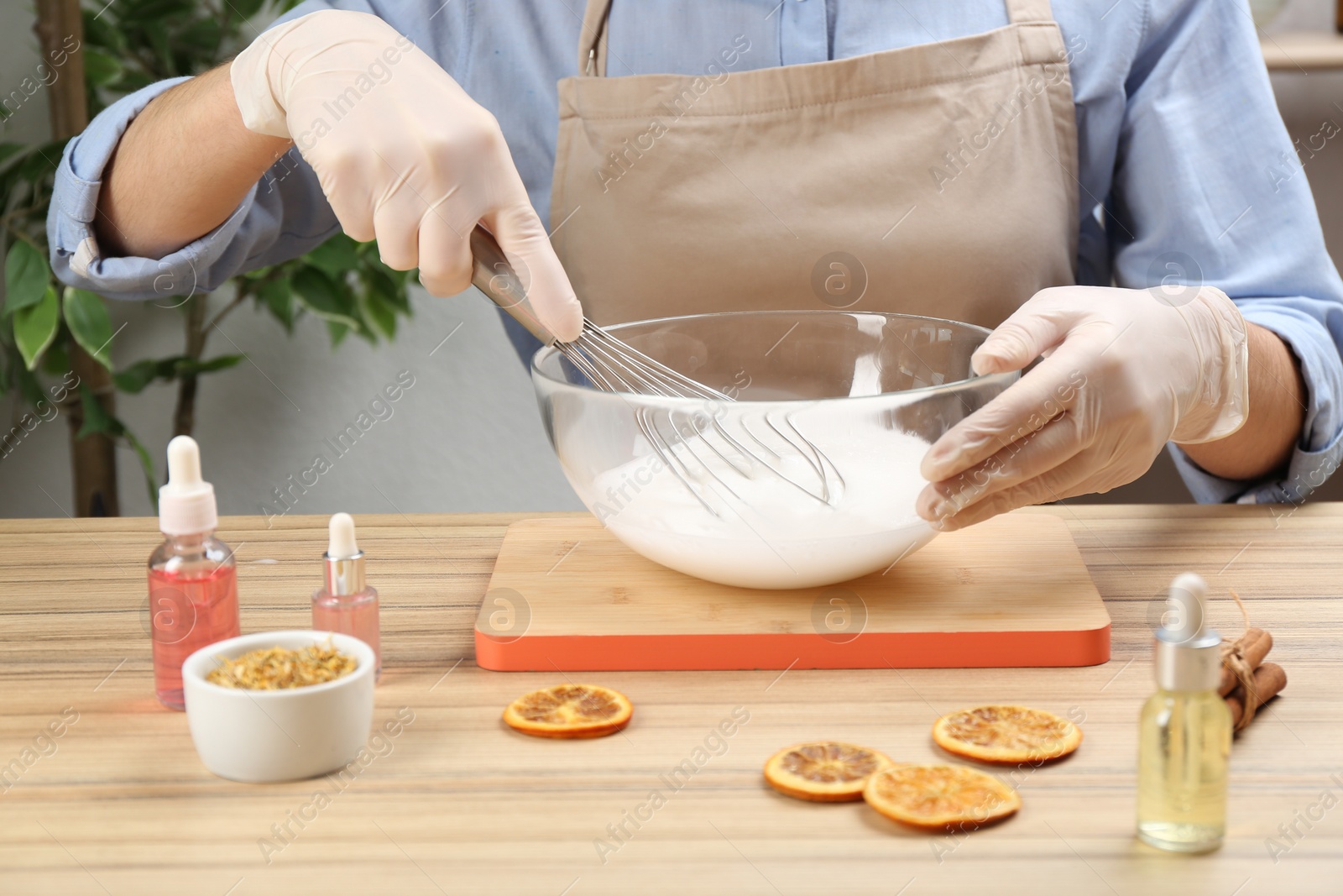 Photo of Woman making natural handmade soap at wooden table, closeup