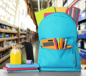 Image of Bright backpack with school stationery on table in shopping mall