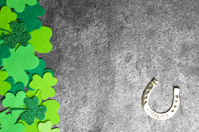 Photo of Flat lay composition with clover leaves and horseshoe on grey stone background, space for text. St. Patrick's day