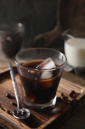 Photo of Glass of delicious iced coffee and beans on wooden board