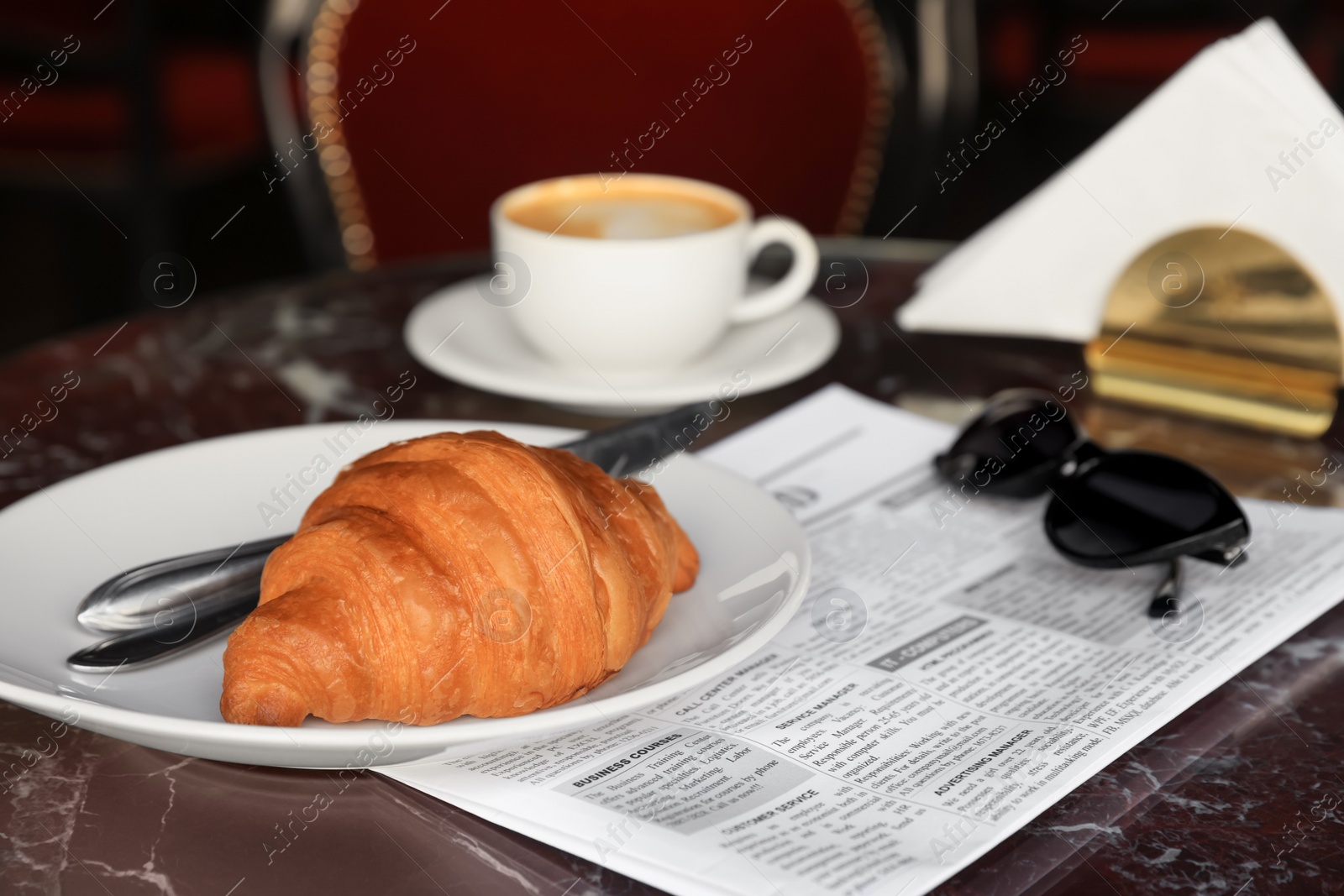 Photo of Tasty croissant and cup of aromatic coffee on black table