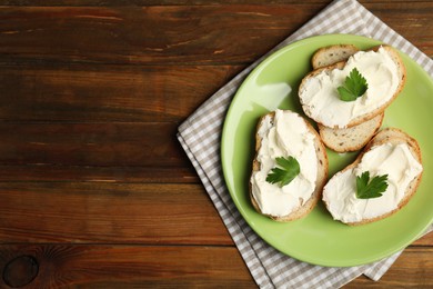 Photo of Bread with cream cheese and parsley on wooden table, top view. Space for text
