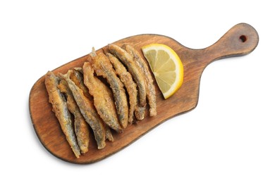 Photo of Wooden board with delicious fried anchovies and lemon on white background, top view