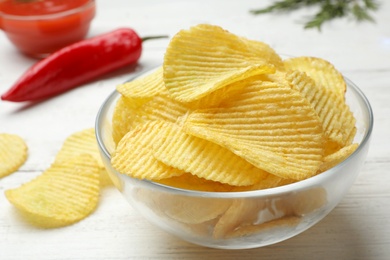 Photo of Delicious crispy potato chips in bowl on table, closeup