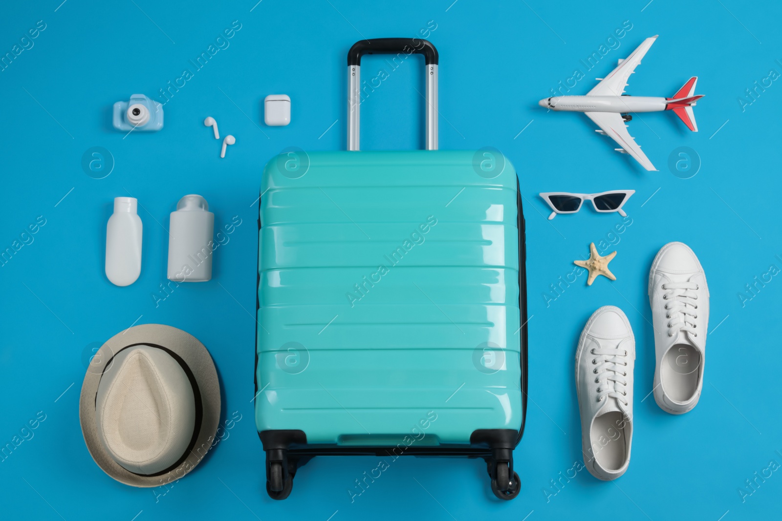 Photo of Flat lay composition with suitcase and travel accessories on light blue background. Summer vacation