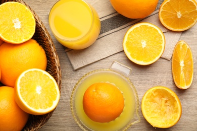 Photo of Squeezer, fresh oranges and juice on wooden table, flat lay
